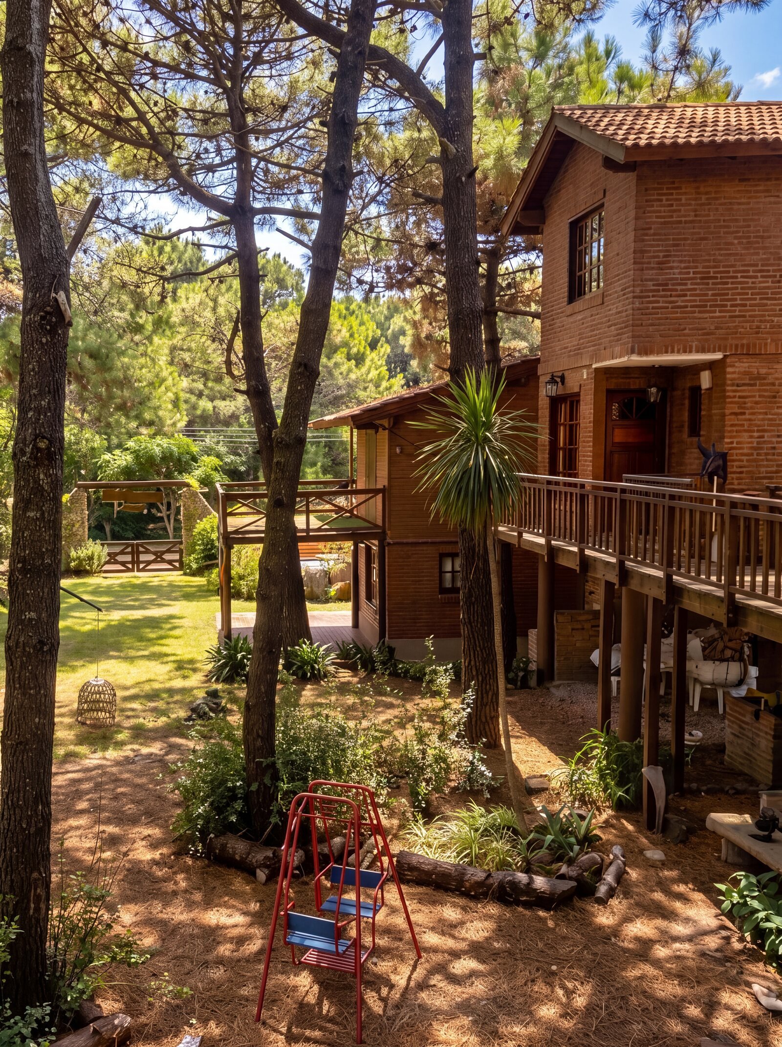 Jardín del complejo con pinos altos y juegos para chicos