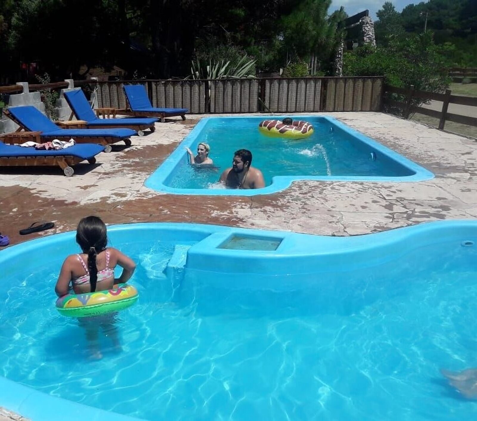 Familias disfrutando de las dos piletas del complejo en verano, con reposeras al sol